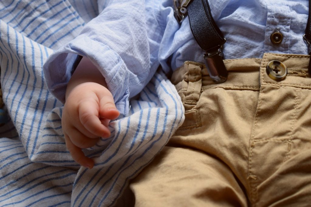 bébé qui porte une chemise bleu et un pantalon marron